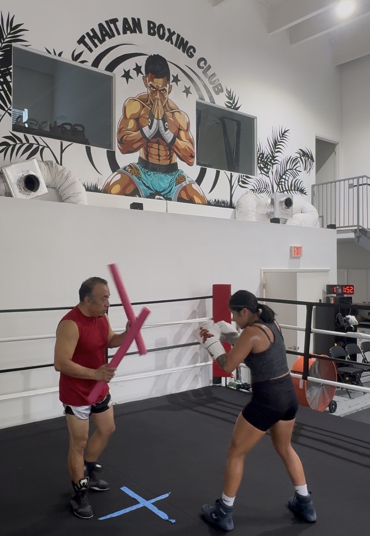 Woman training with a coach in the ring at Thaitan Boxing Club